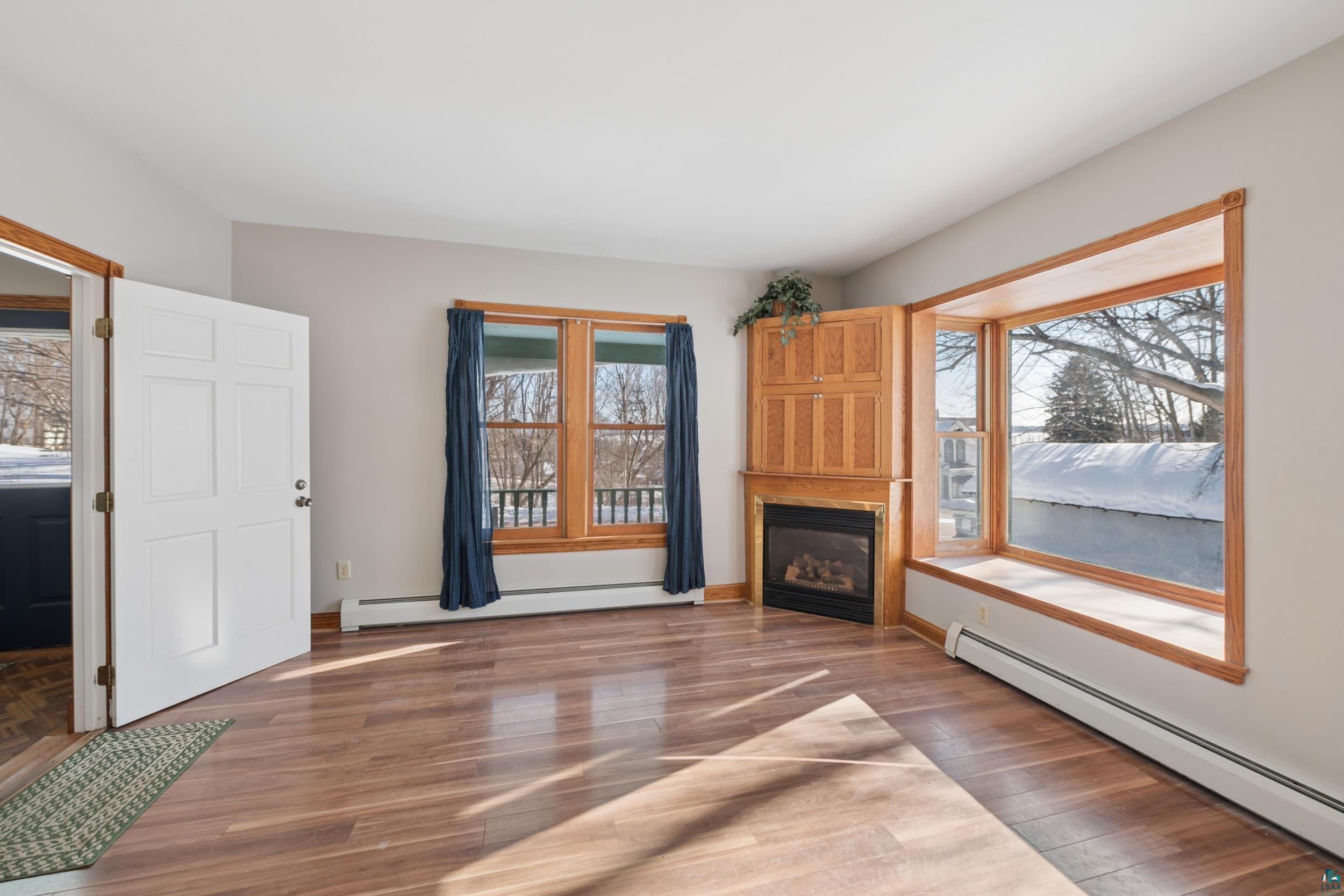 33 South 4th Street Bayfield, WI 54814 - Photo 8 of 29 Unfurnished living room with a baseboard radiator, wood finished floors, and a glass covered fireplace