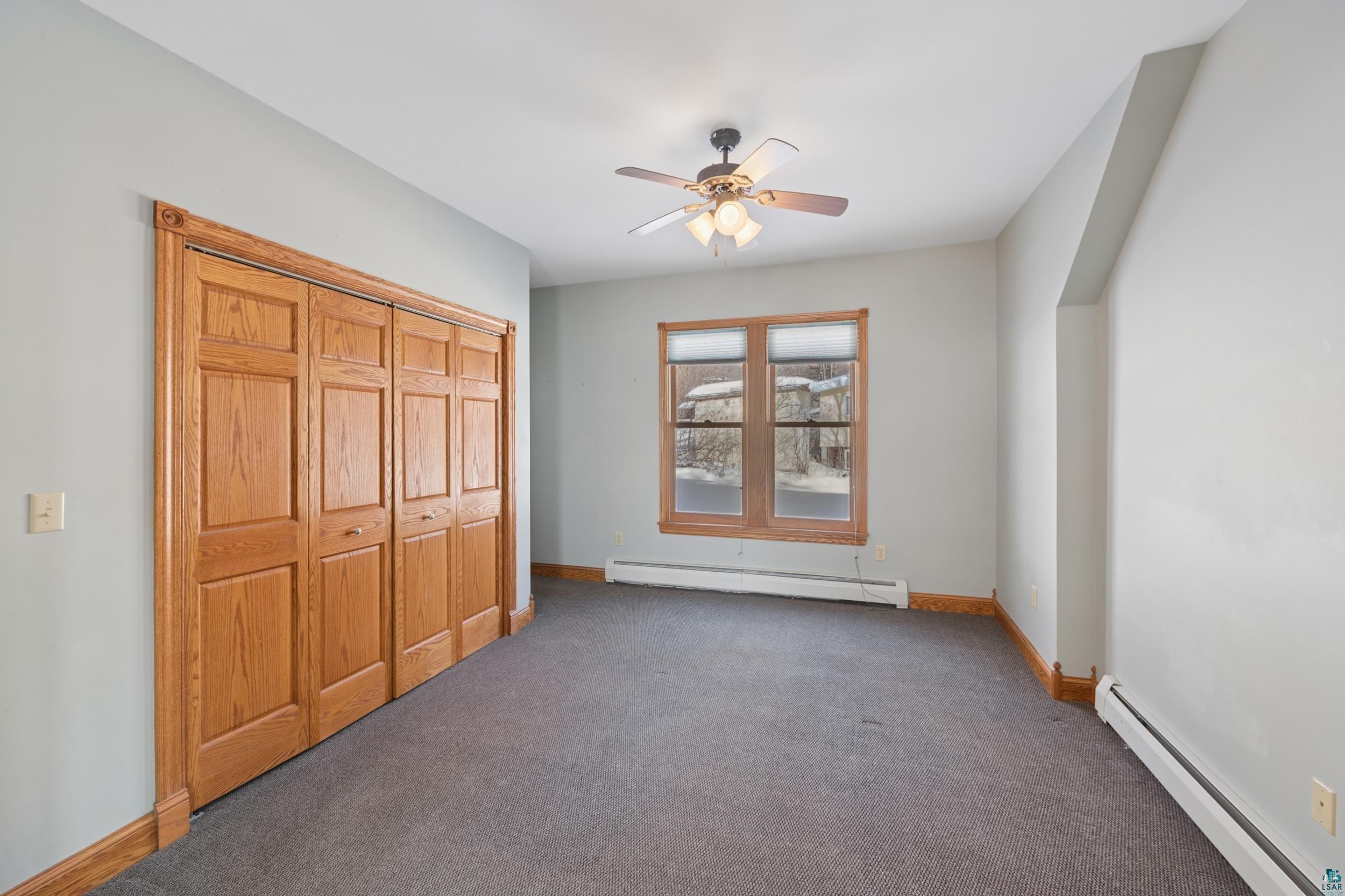 33 South 4th Street Bayfield, WI 54814 - Photo 9 of 29 Unfurnished bedroom featuring a baseboard radiator, carpet flooring, a closet, and ceiling fan