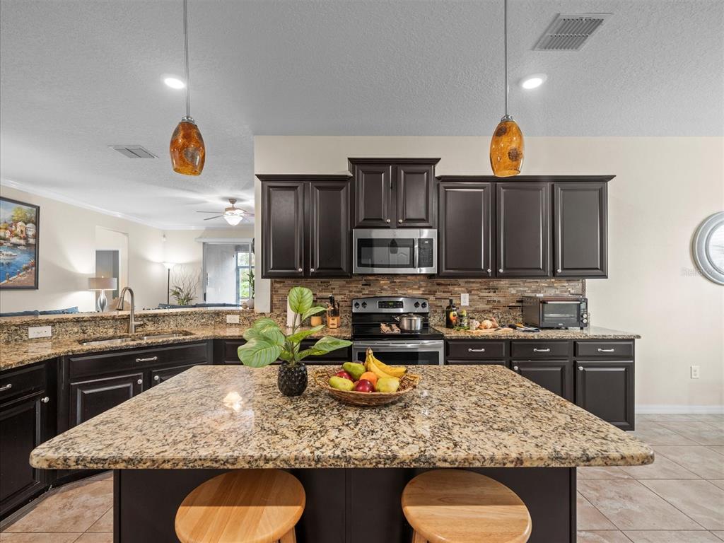 12722 Drakefield Drive Spring Hill, FL 34610 - Photo 13 of 45 a kitchen with stainless steel appliances granite countertop a sink stove and refrigerator
