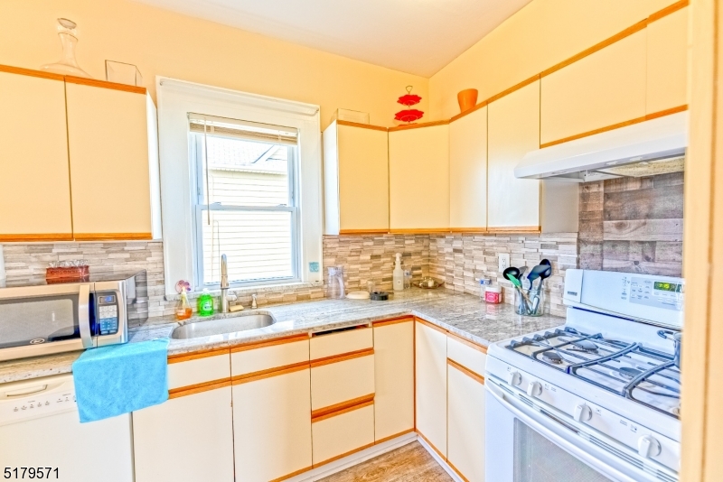 146 Main Street, Unit 2 Garfield, NJ 07026 - Photo 13 of 14 a kitchen with stainless steel appliances kitchen island wooden cabinets a sink and a large window
