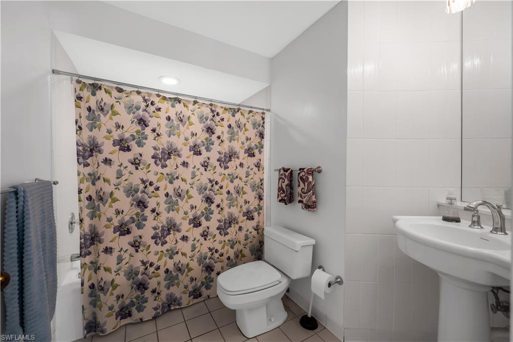 183 Edgemere Way South Naples, FL 34105 - Photo 15 of 42 Bathroom with tile walls, light tile patterned floors, and shower / bath combination with curtain