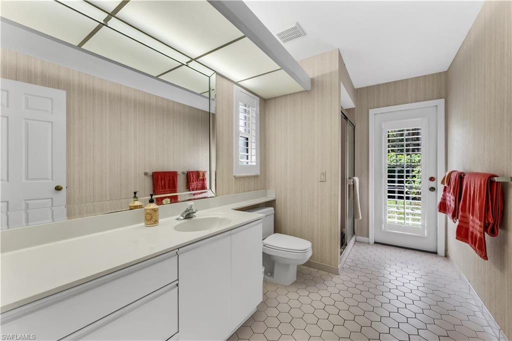 183 Edgemere Way South Naples, FL 34105 - Photo 17 of 42 Bathroom featuring plenty of natural light, vanity, a shower stall, and wallpapered walls. Exits to pool area.