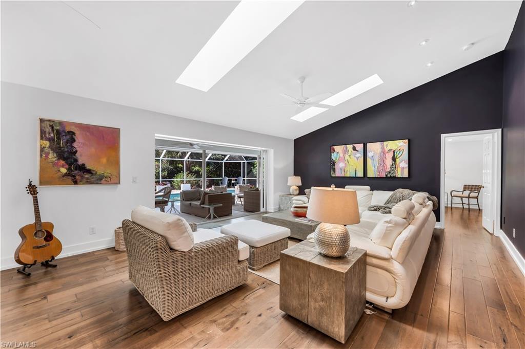 183 Edgemere Way South Naples, FL 34105 - Photo 3 of 42 Living area with wood-type flooring, a ceiling fan, a sunroom, vaulted ceiling, and a skylight