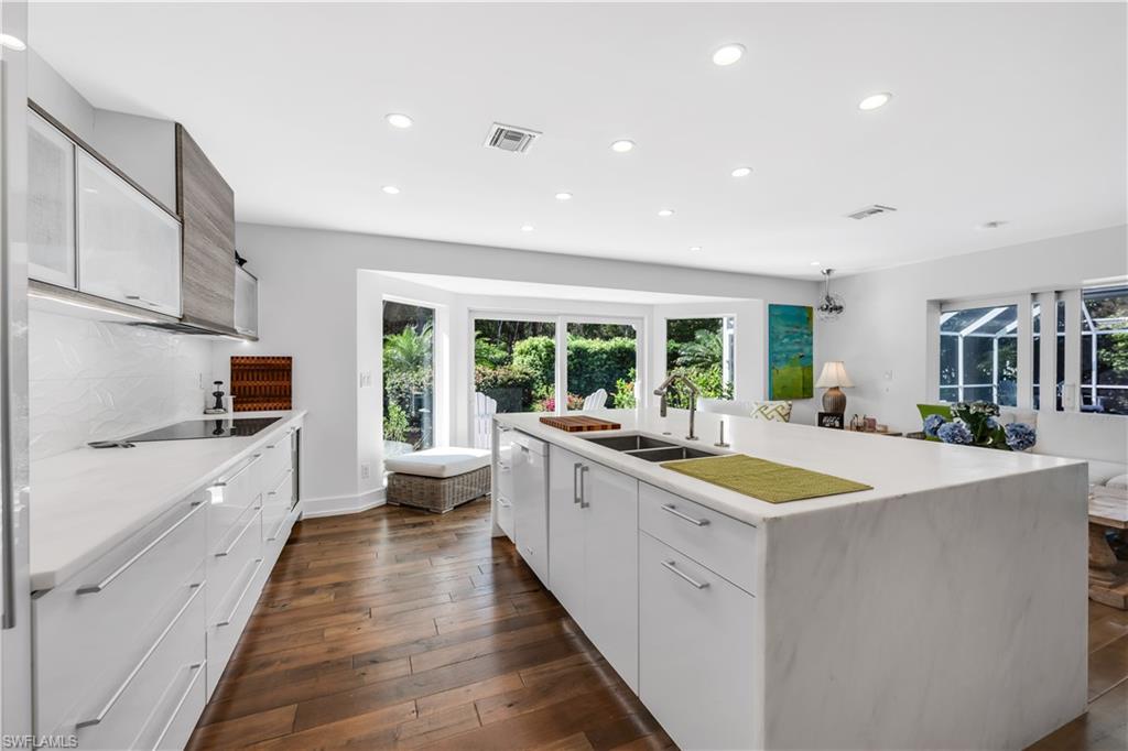 183 Edgemere Way South Naples, FL 34105 - Photo 10 of 42 Kitchen featuring an island with sink, recessed lighting, modern cabinets, dark wood-type flooring, and light stone countertops