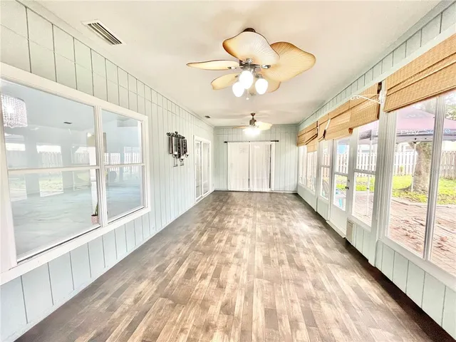 an empty room with windows and fan