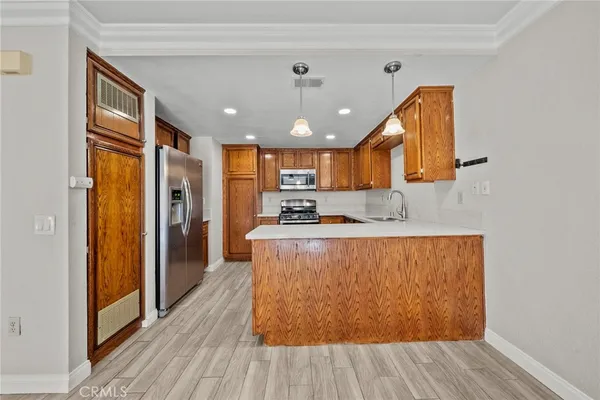 a large kitchen with stainless steel appliances granite countertop a refrigerator a sink dishwasher a stove and white countertops with wooden floor