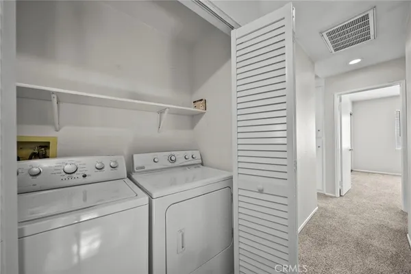 a view of washer and dryer with bathroom in the background