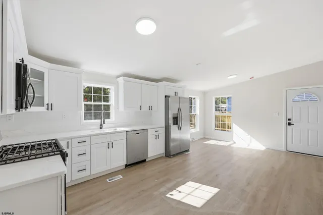 a kitchen with a sink a stove a refrigerator and white cabinets