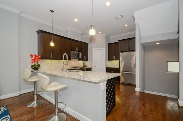 a kitchen with stainless steel appliances kitchen island granite countertop a refrigerator a stove a sink dishwasher and a dining table with wooden floor