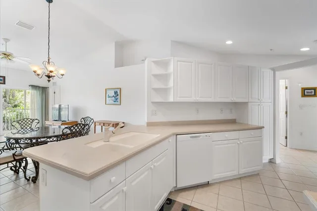 a kitchen with a sink dishwasher and white cabinets with wooden floor