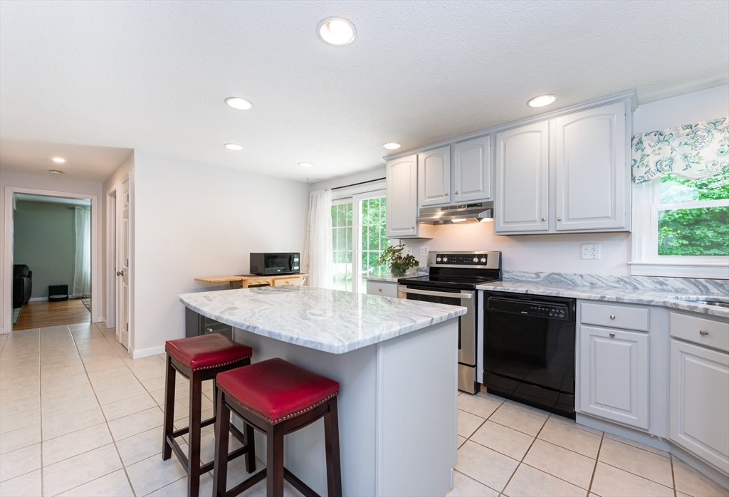 11 Emerson Road Nashua, NH 03062 - Photo 11 of 35 a kitchen with granite countertop a stove a sink dishwasher a dining table and chairs with wooden floor