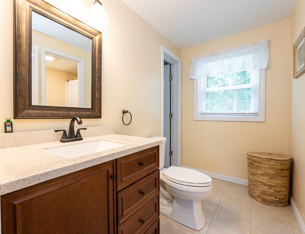 11 Emerson Road Nashua, NH 03062 - Photo 25 of 35 a bathroom with a granite countertop toilet a sink a mirror and a window