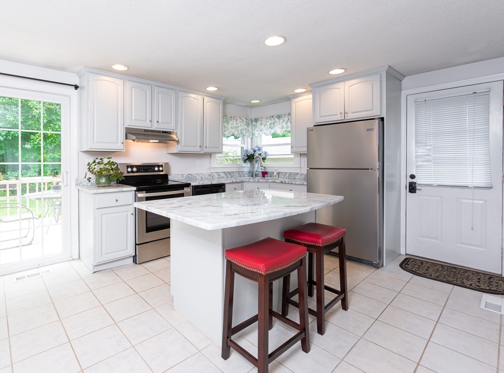 11 Emerson Road Nashua, NH 03062 - Photo 8 of 35 a kitchen with stainless steel appliances a stove a sink a refrigerator and white cabinets with wooden floor