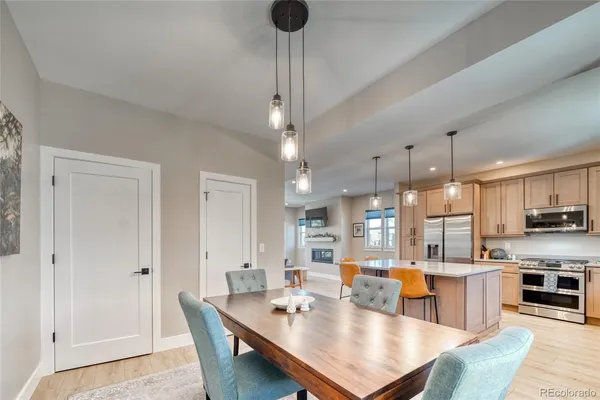 a room with stainless steel appliances kitchen island granite countertop a table chairs and a refrigerator