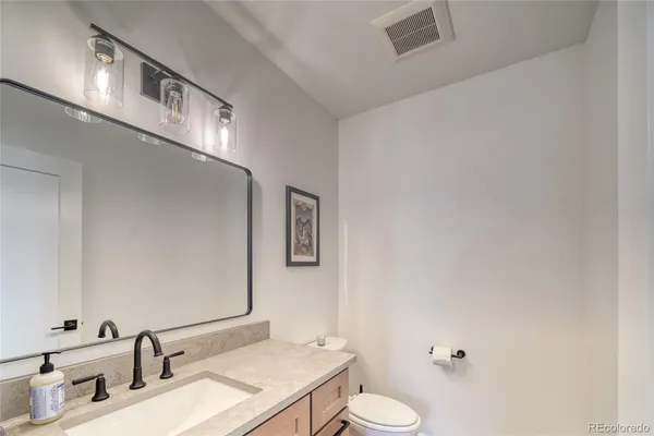 a bathroom with a granite countertop sink and a toilet