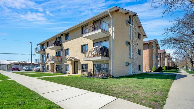 a view of a white house next to a yard with big trees