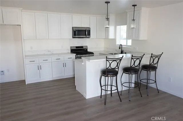 a kitchen with stainless steel appliances a white table and chairs in it