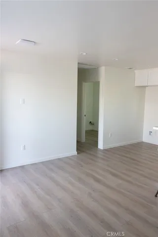 a view of an empty room with wooden floor and closet
