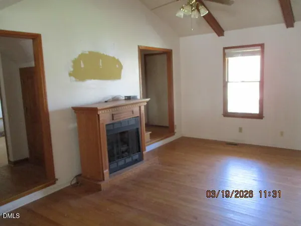 an empty room with a fireplace and wooden floor