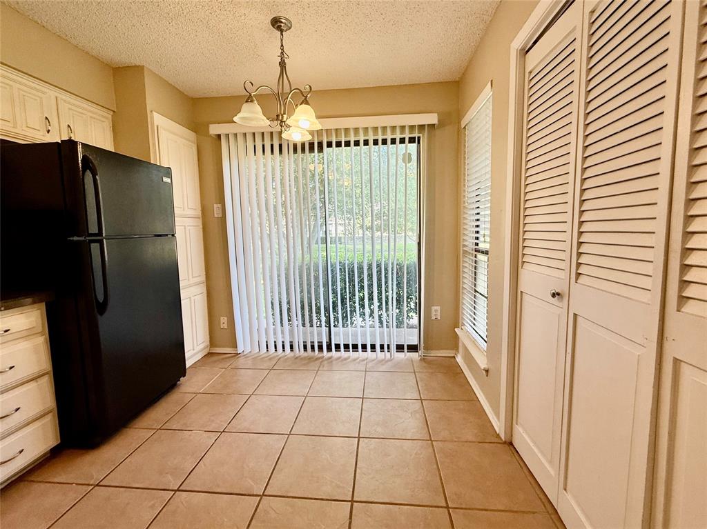 777 Custer Road, Unit 23 Richardson, TX 75080 - Photo 11 of 28 Kitchen with freestanding refrigerator, light tile patterned flooring, a chandelier, decorative light fixtures, and a textured ceiling