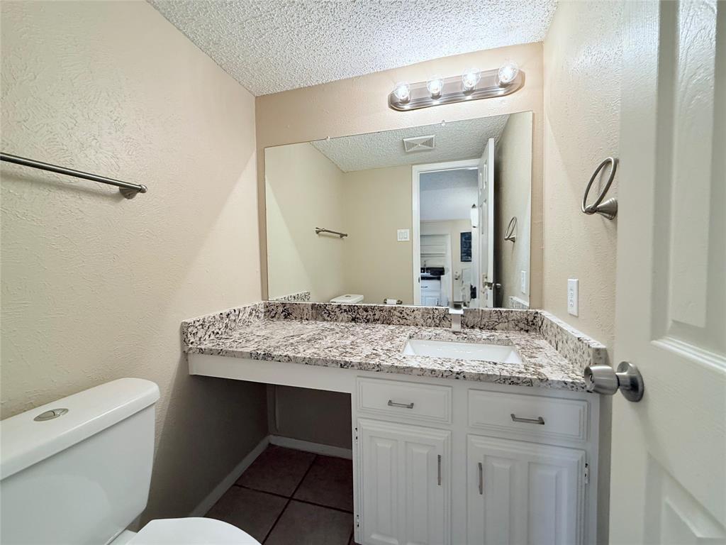 777 Custer Road, Unit 23 Richardson, TX 75080 - Photo 14 of 28 Bathroom with vanity, a textured wall, a textured ceiling, and tile patterned floors