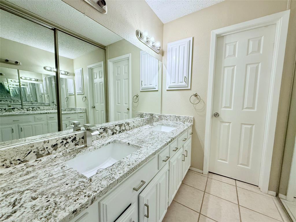 777 Custer Road, Unit 23 Richardson, TX 75080 - Photo 17 of 28 Full bath featuring double vanity, light tile patterned floors, and a textured ceiling