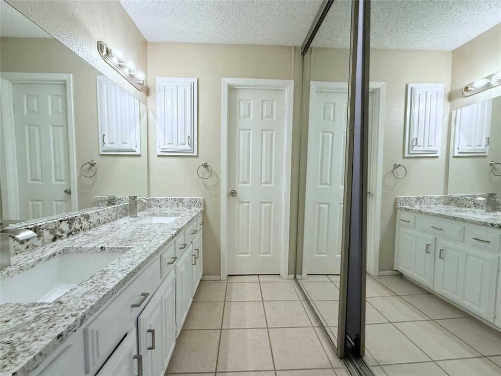 777 Custer Road, Unit 23 Richardson, TX 75080 - Photo 18 of 28 Full bath featuring double vanity, light tile patterned flooring, and a textured ceiling