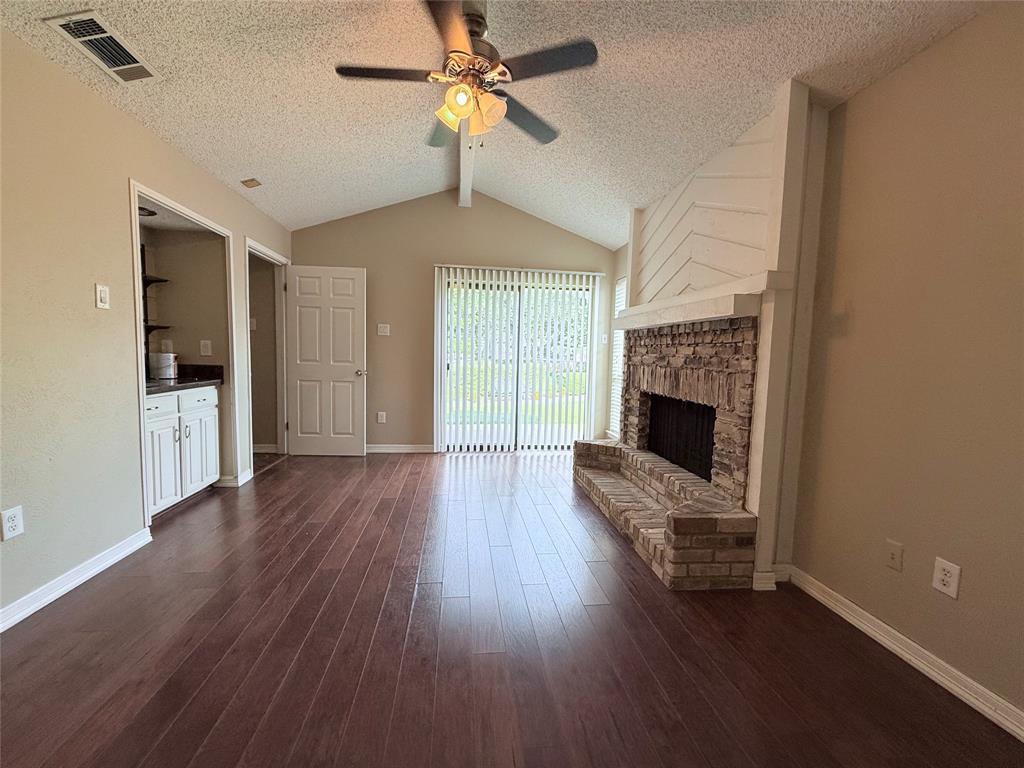 777 Custer Road, Unit 23 Richardson, TX 75080 - Photo 20 of 28 Unfurnished living room with dark wood finished floors, a textured ceiling, ceiling fan, and a fireplace
