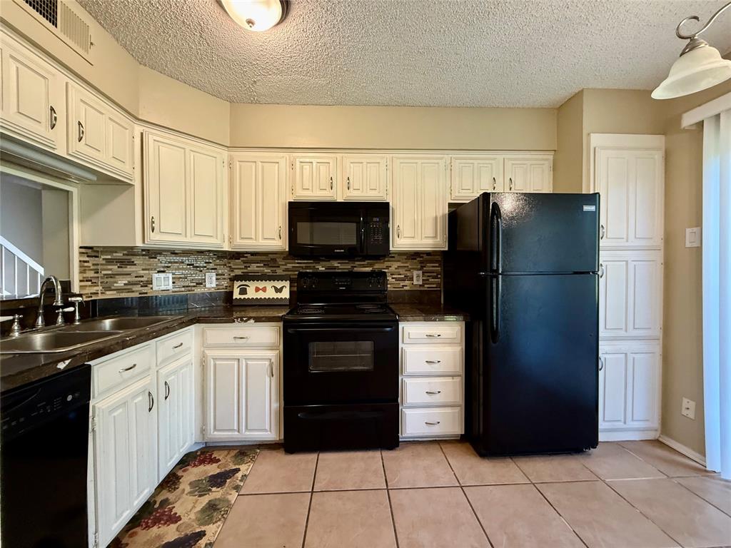 777 Custer Road, Unit 23 Richardson, TX 75080 - Photo 2 of 28 Kitchen with black appliances, tasteful backsplash, a textured ceiling, light tile patterned floors, and white cabinets