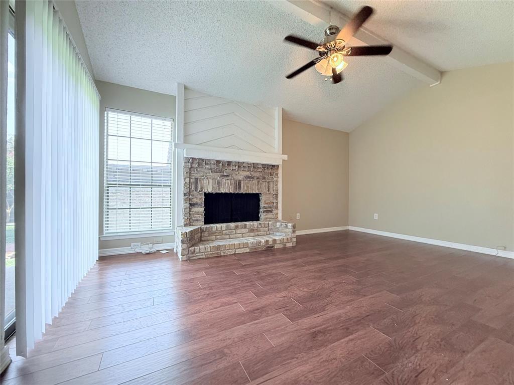777 Custer Road, Unit 23 Richardson, TX 75080 - Photo 21 of 28 Unfurnished living room featuring a textured ceiling, dark wood-style floors, a fireplace, and ceiling fan