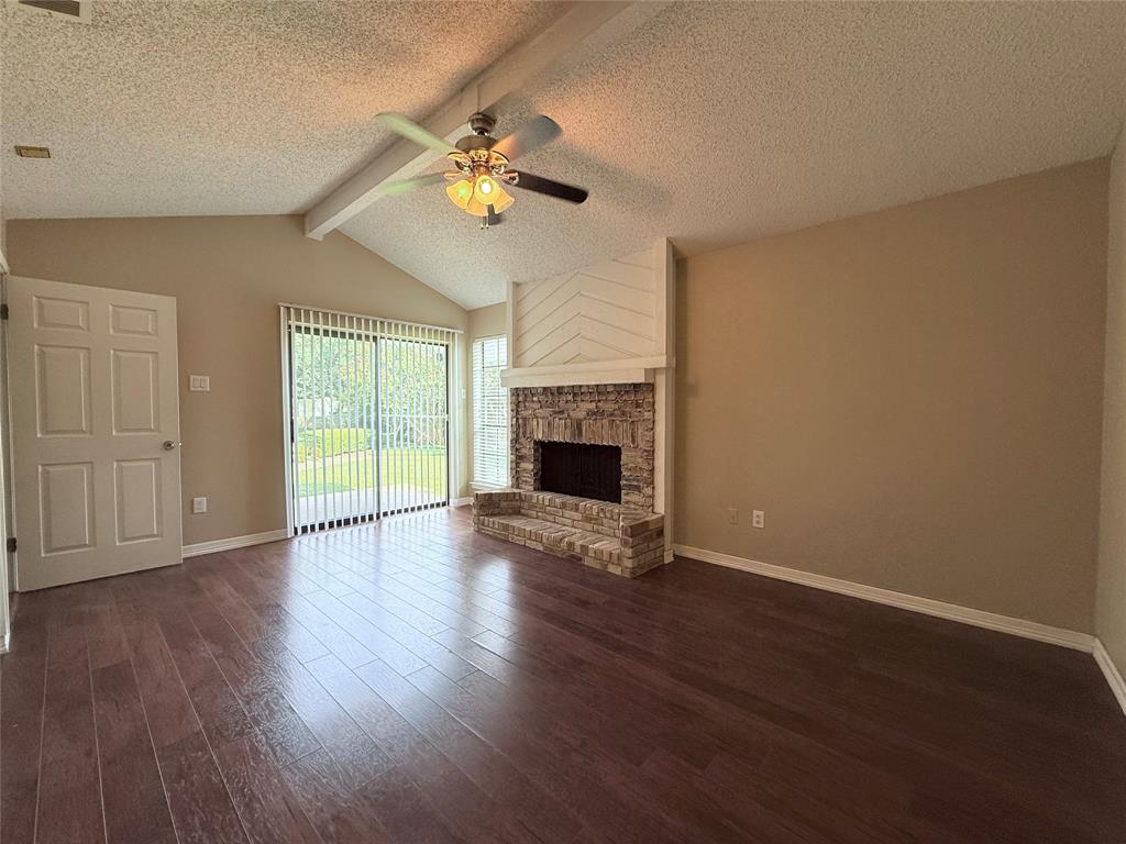 777 Custer Road, Unit 23 Richardson, TX 75080 - Photo 22 of 28 Unfurnished living room featuring dark wood-style flooring, a fireplace, a textured ceiling, and ceiling fan