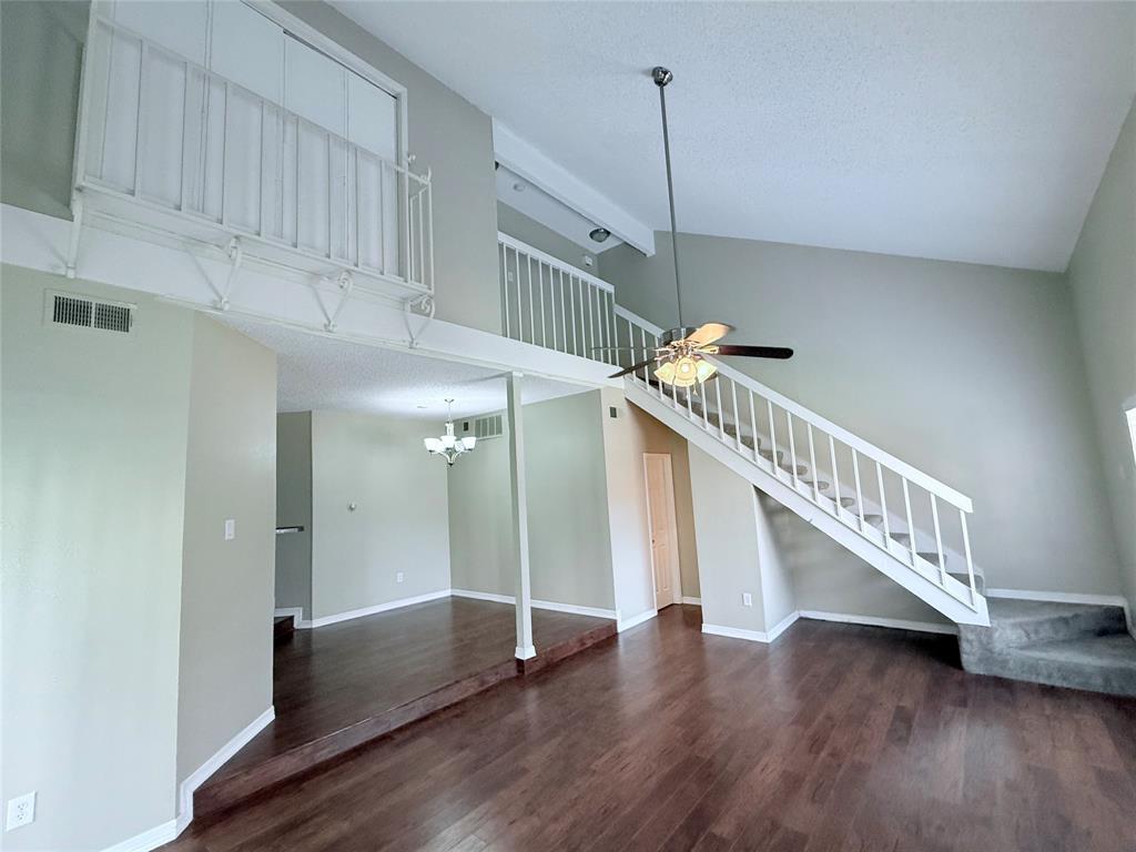 777 Custer Road, Unit 23 Richardson, TX 75080 - Photo 4 of 28 Unfurnished living room with a ceiling fan, dark wood finished floors, beam ceiling, high vaulted ceiling, and stairs
