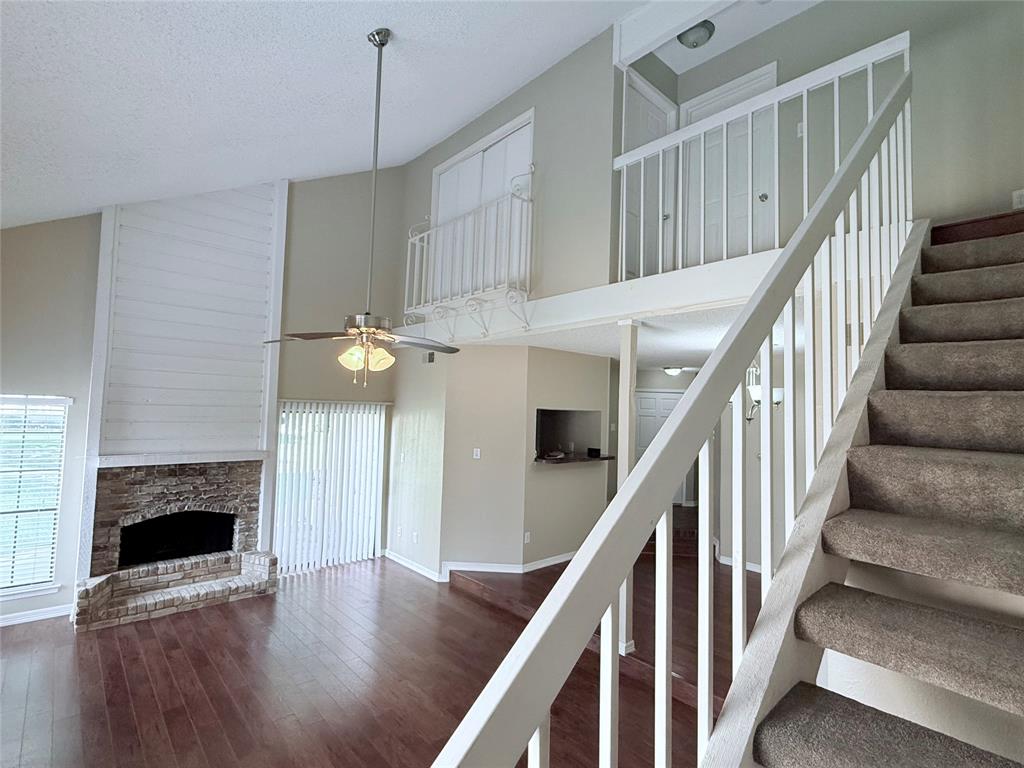 777 Custer Road, Unit 23 Richardson, TX 75080 - Photo 5 of 28 Staircase with high vaulted ceiling, wood finished floors, a textured ceiling, a stone fireplace, and ceiling fan
