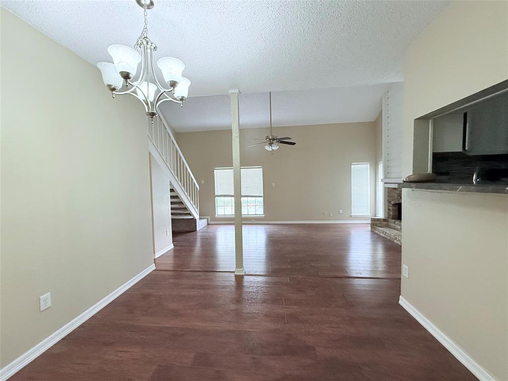 777 Custer Road, Unit 23 Richardson, TX 75080 - Photo 6 of 28 Unfurnished living room with dark wood finished floors, stairway, a chandelier, a textured ceiling, and a ceiling fan