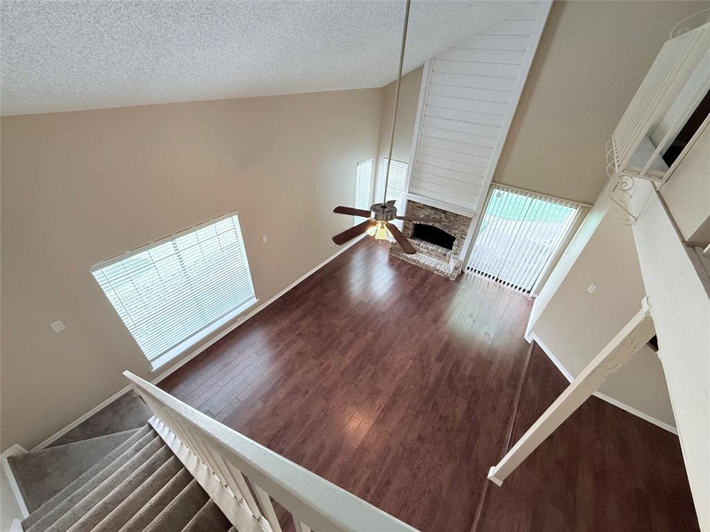 777 Custer Road, Unit 23 Richardson, TX 75080 - Photo 8 of 28 Unfurnished living room featuring high vaulted ceiling, wood finished floors, a textured ceiling, and a fireplace