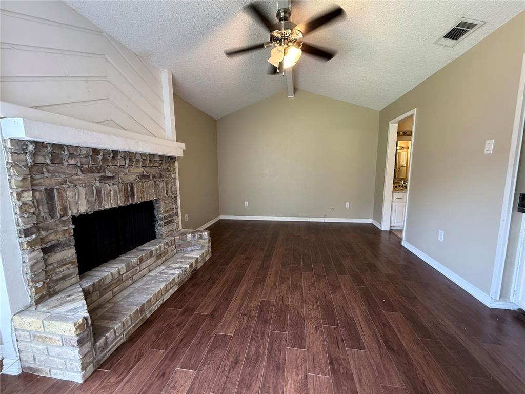 777 Custer Road, Unit 23 Richardson, TX 75080 - Photo 9 of 28 Unfurnished living room featuring a textured ceiling, dark wood finished floors, ceiling fan, and a fireplace