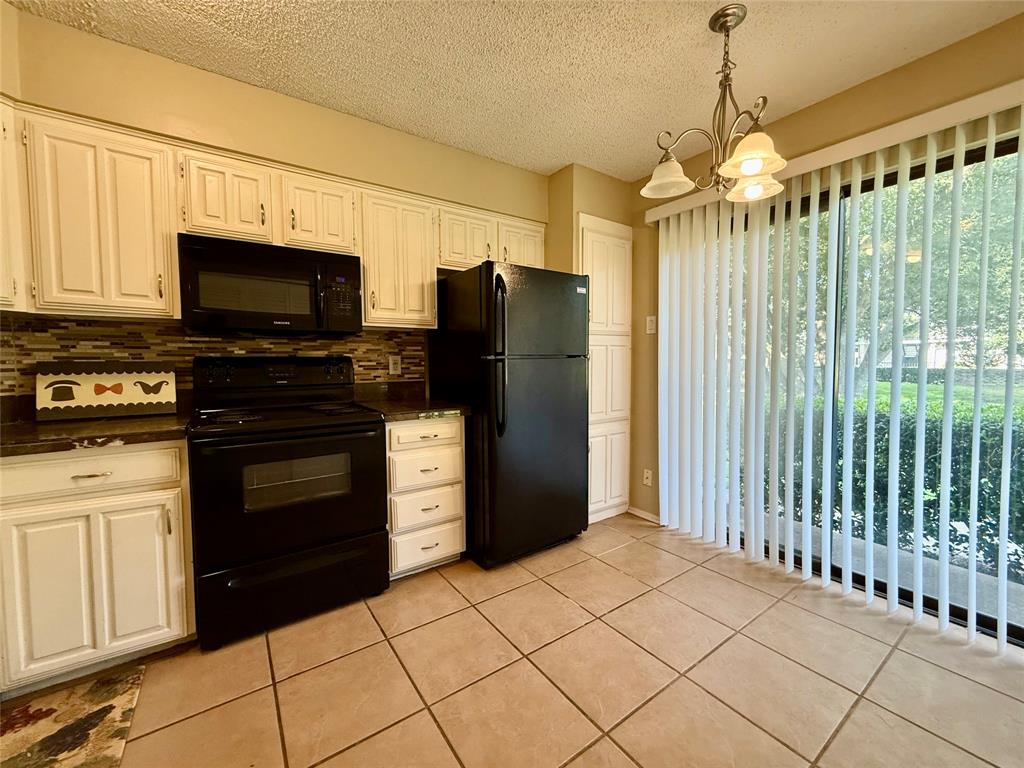 777 Custer Road, Unit 23 Richardson, TX 75080 - Photo 10 of 28 Kitchen featuring black appliances, light tile patterned floors, a chandelier, decorative backsplash, and a textured ceiling