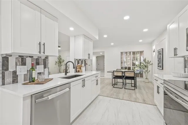 a kitchen with white cabinets sink and stove