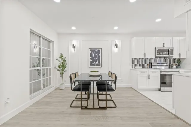 a kitchen with granite countertop a table chairs a sink dishwasher stove and cabinets with wooden floor