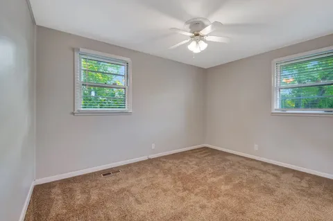 an empty room with windows and ceiling fan