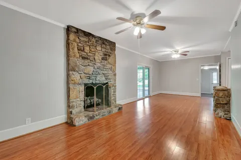 a view of a livingroom with wooden floor a ceiling fan and a fireplace
