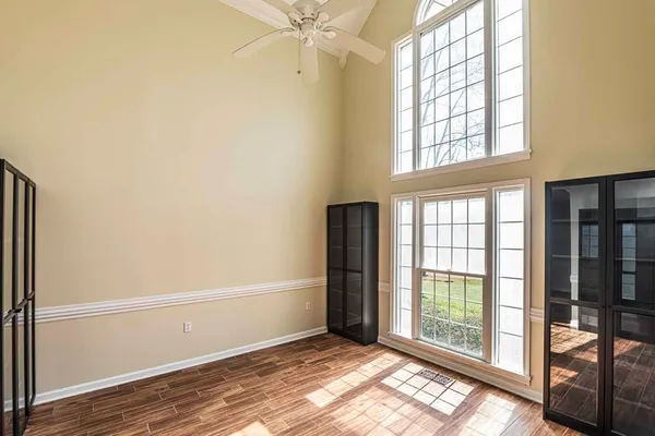 a view of an empty room with wooden floor and a window