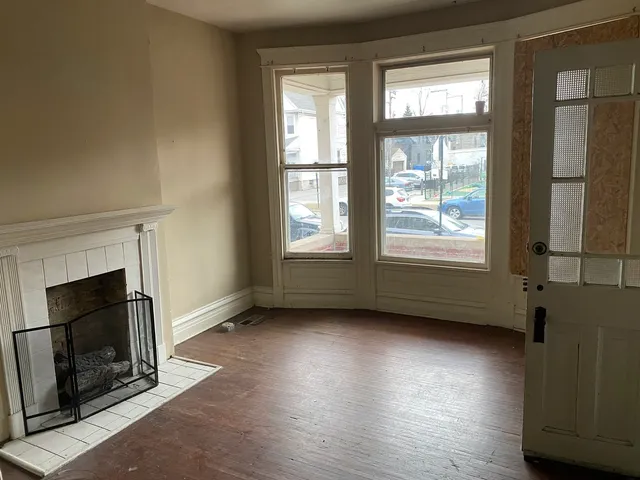an empty room with wooden floor fireplace and windows