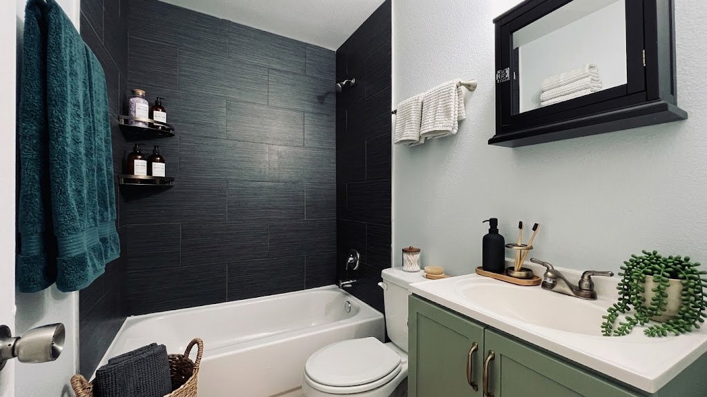2301 Ohlen Road, Unit 109 Austin, TX 78757 - Photo 6 of 7 Textured dark wall tiles contrast with a classic white tub in this updated bathroom.
