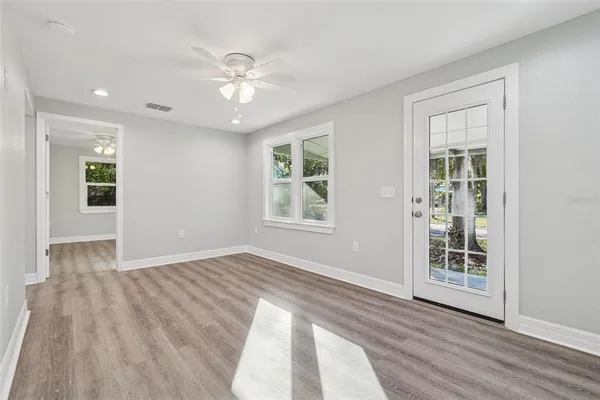 a view of an empty room with wooden floor and a window