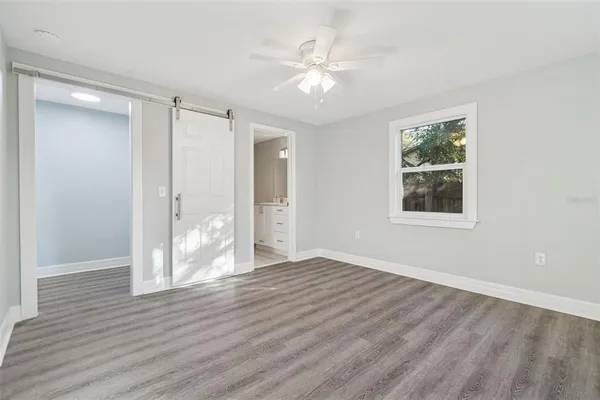 a view of an empty room with wooden floor and a window