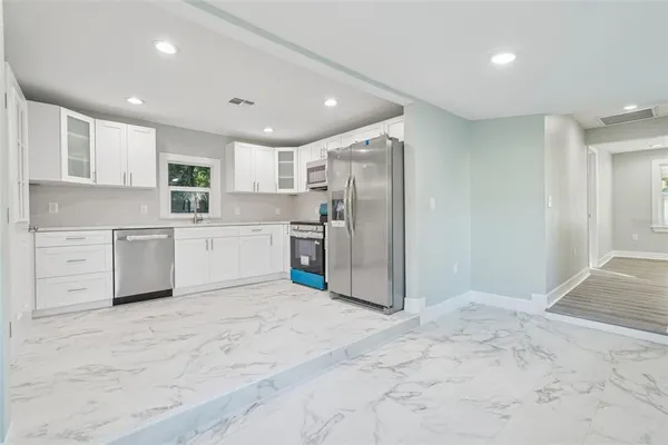 a large white kitchen with cabinets and stainless steel appliances