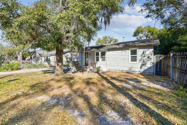 a view of a house with a yard and large tree