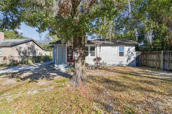 a view of a house with a yard and large tree