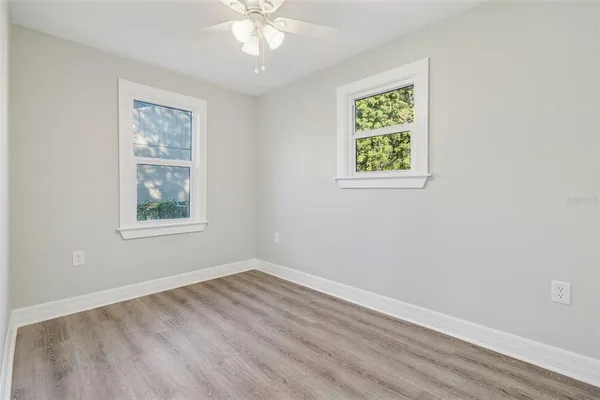 a view of an empty room with a window and wooden floor
